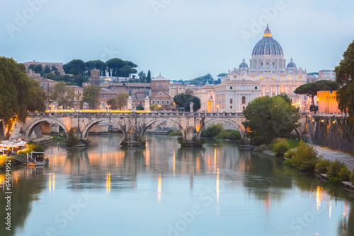 Sceninc twilight view of Saint Peter's Basilica at Vatican City and Ponte Vittorio Emanuele II illuminated along the Tiber River on a summer evening in Rome, Italy. photo