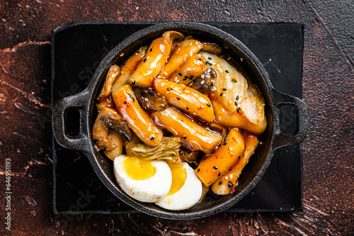 Korean Topokki or Tteokbokki rice cake with egg and mashrooms. Dark background. Top view