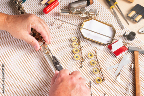 repairing a flute in the foreground. two hands removing a shaft with pliers. photo