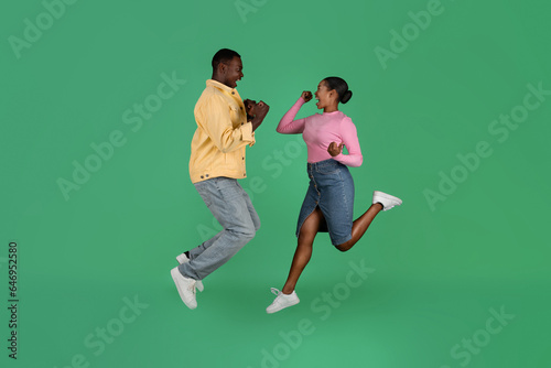 Thrilled african american millennial man and woman gesturing and jumping