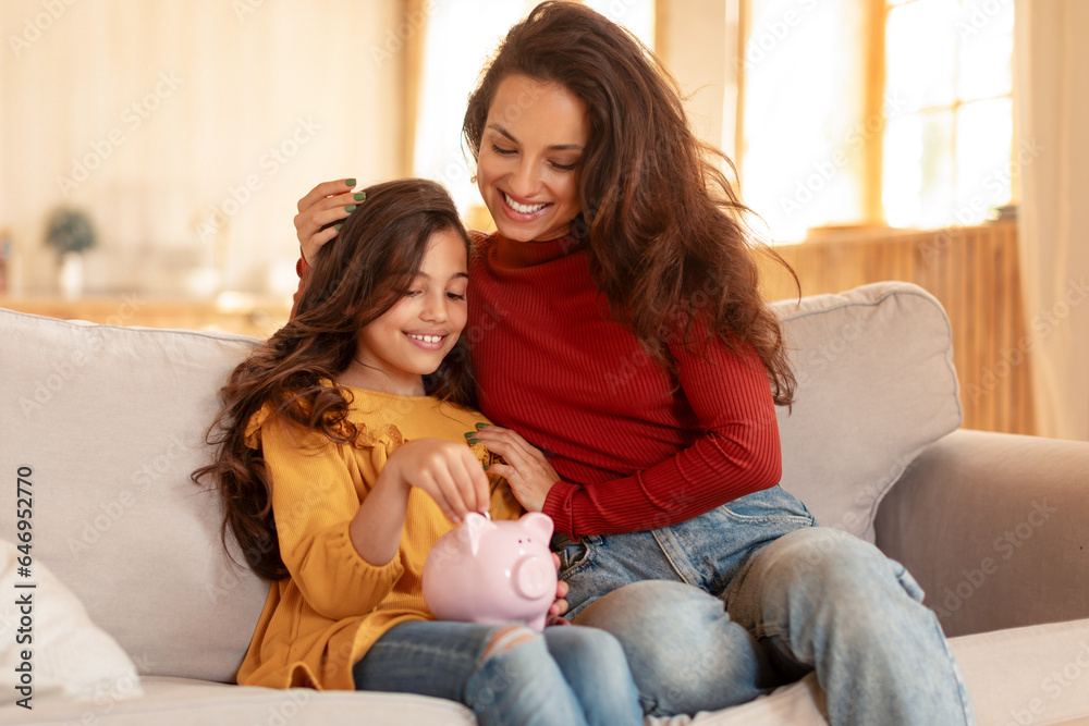 Arabic Mommy and Daughter Sharing Joy of Saving Money Indoors