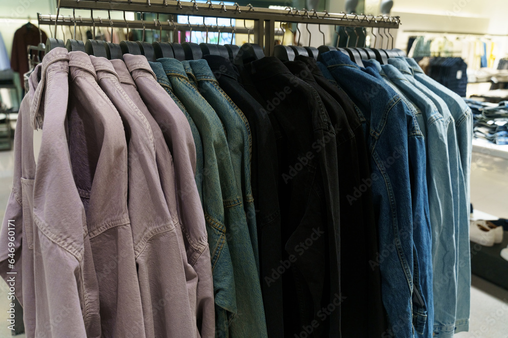 Denim shirts with long sleeves hang on hangers in a clothing store. Denim shirts with long sleeves hang on hangers in a clothing store.
