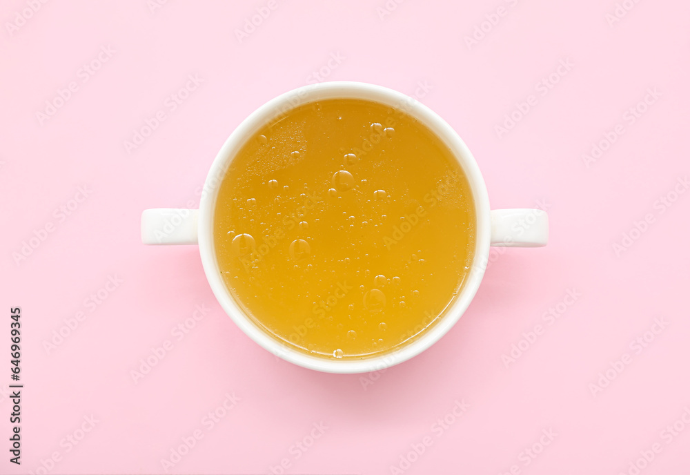 Pot of tasty vegetable broth on pink background Pot of tasty vegetable broth on pink background
