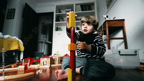Little boy building a tower block, putting vintage blocks on top of one another, kid immersed in his own world, concentrated and playing by himself