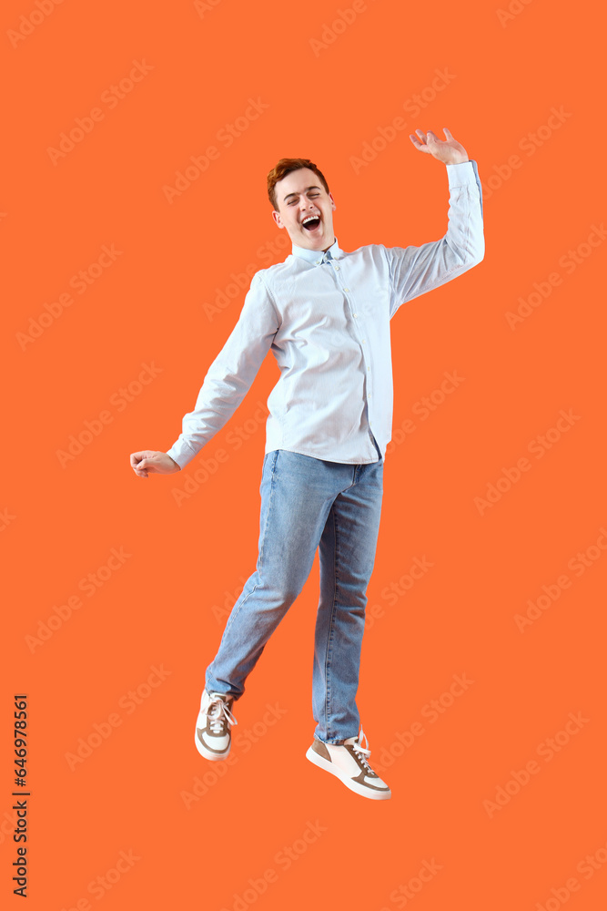 Happy jumping young man on orange background Happy jumping young man on orange background