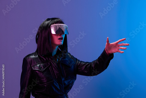 Принти на полотні Confused pretty awesome brunet lady in leather jacket trendy specular sunglasses touch invisible object posing isolated in blue violet color light background