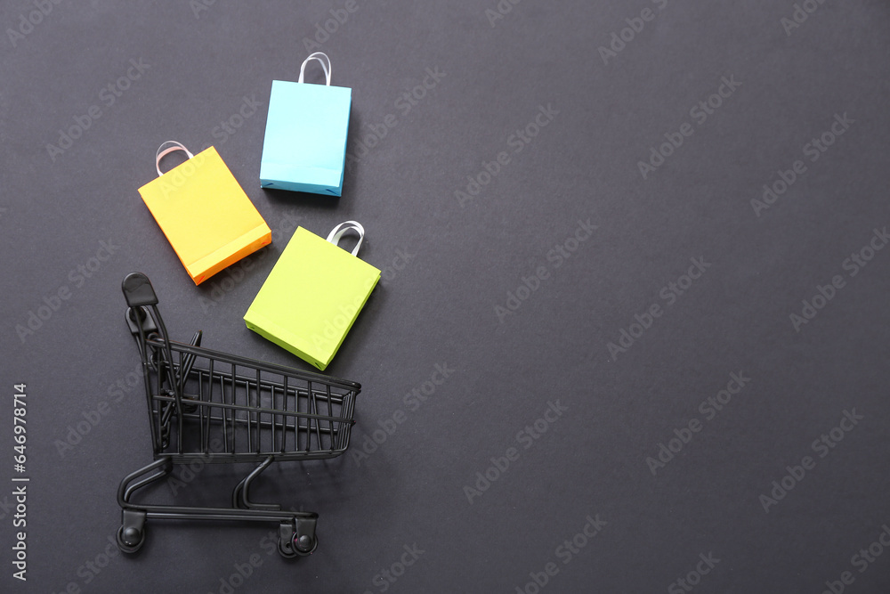 Small shopping cart with bags on black background