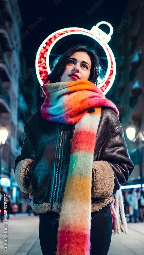 Pretty young girl with scarf admiring the Christmas lights. 