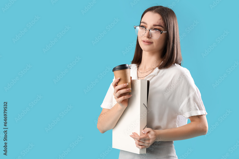 Young businesswoman with folder and cup of coffee on blue background Young businesswoman with folder and cup of coffee on blue background