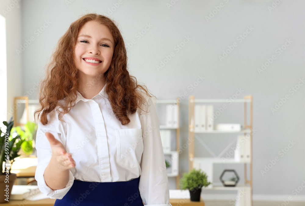 Young businesswoman reaching out for handshake in office Young businesswoman reaching out for handshake in office