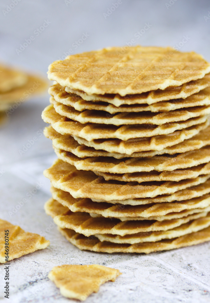 Close-up of a stack of butter waffle cookies on a grey background, selective focus vertical image. Waffle crisps close-up. Tasty home made thin waffles Close-up of a stack of butter waffle cookies on a grey background, selective focus vertical image. Waffle crisps close-up. Tasty home made thin waffles