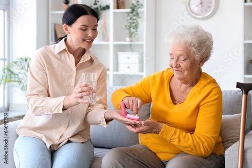 Senior woman with her daughter taking pills at home