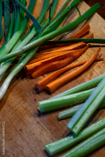 Sliced carrots green onions and celery on a wooden background