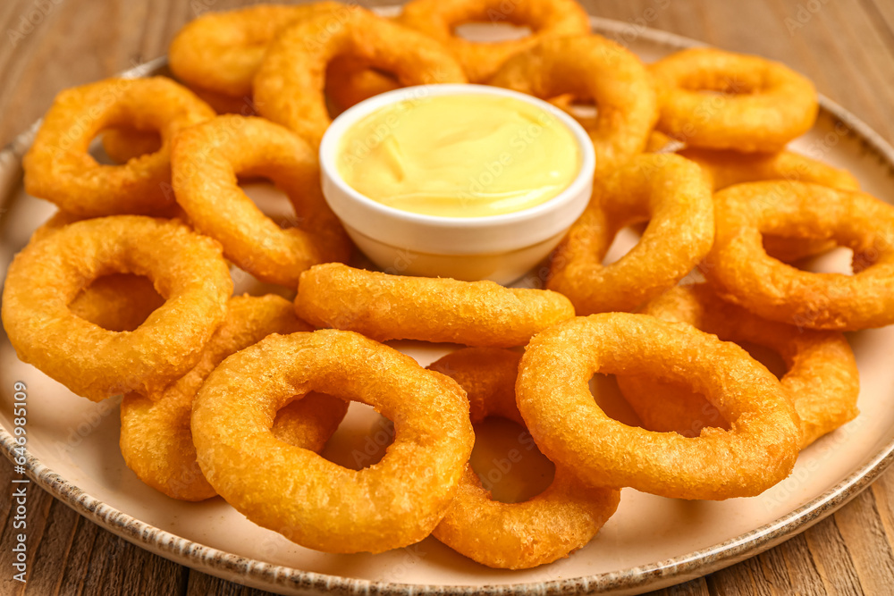 Plate with fried breaded onion rings and mayonnaise on wooden background, closeup Plate with fried breaded onion rings and mayonnaise on wooden background, closeup