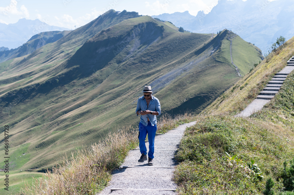 Young man on an alpine hike in the Swiss mountains. He is photographing the beautiful landscape.