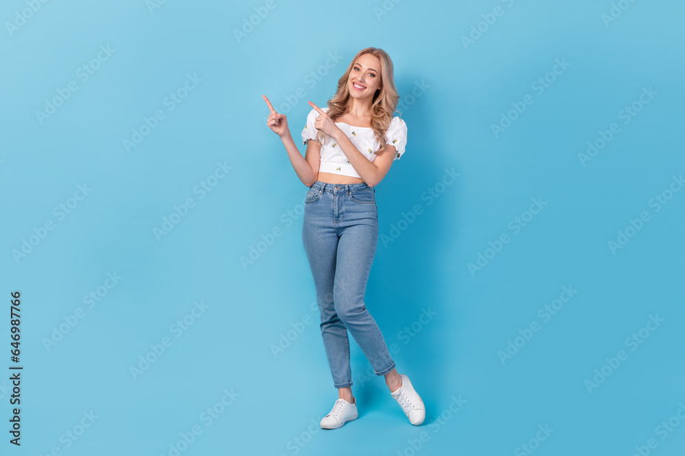 Full length photo of sweet cute lady wear white blouse pointing two fingers empty space isolated blue color background