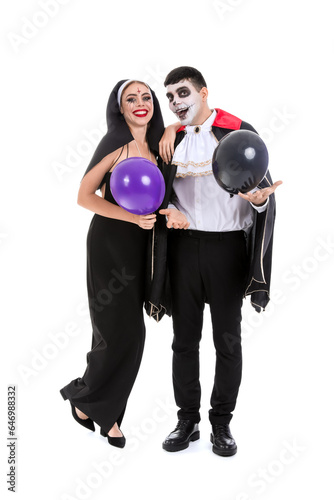 Young couple in costumes for Halloween party with balloons on white background