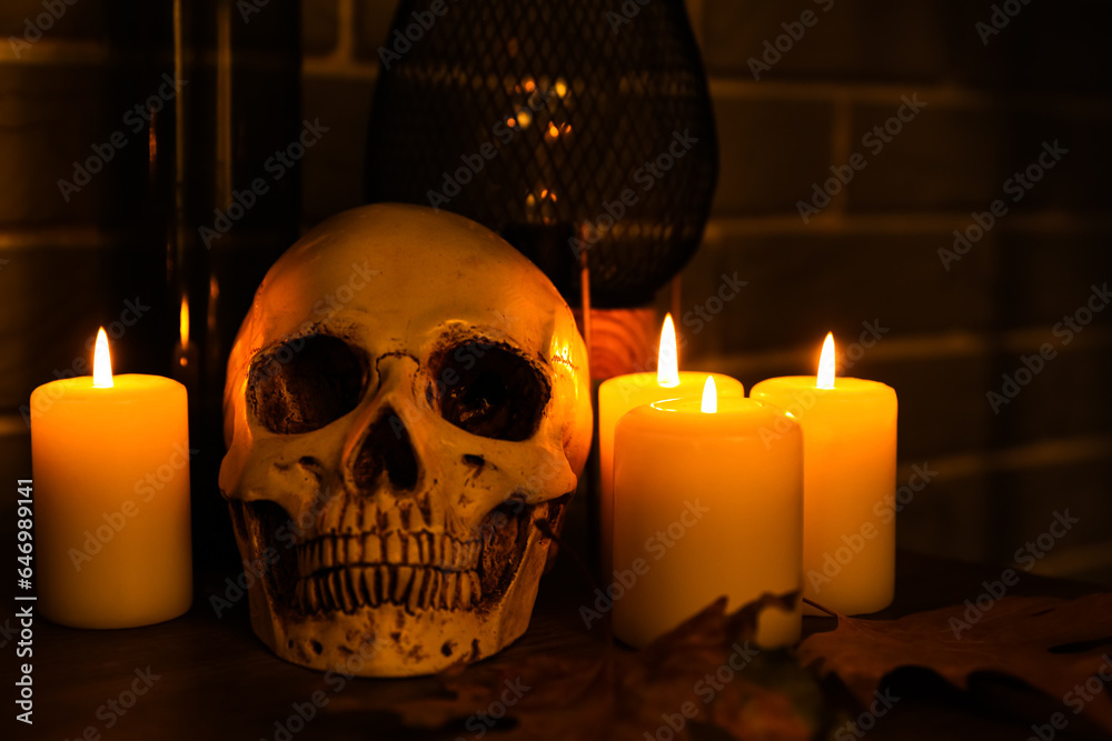 Human skull with burning candles on mantelpiece in dark room, closeup Human skull with burning candles on mantelpiece in dark room, closeup