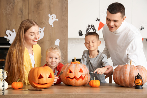 Happy family carving Halloween pumpkins in kitchen photo