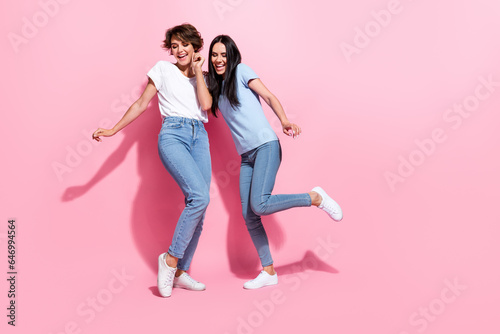 Full body length cadre of two young optimistic ladies chill vibe dance store black friday advert outlet isolated on pink color background