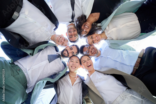 Multiracial diverse group of office men women colleagues hugging in circle looking down smiling camera. Portrait of cheerful male and female business people in suits together. Team gathered outdoors.