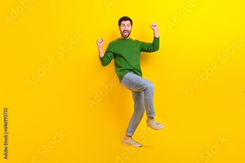 Full length body photo of funny overjoyed young man fists up celebrate his championship promotion isolated on yellow color background