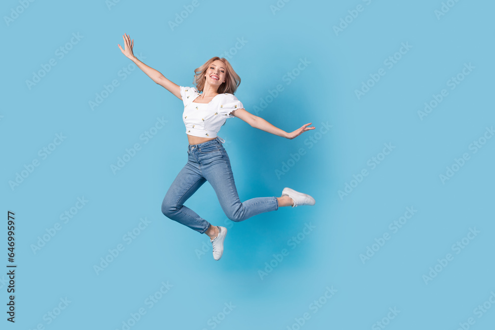 Full length photo of sweet carefree lady wear white blouse jumping high flying empty space isolated blue color background