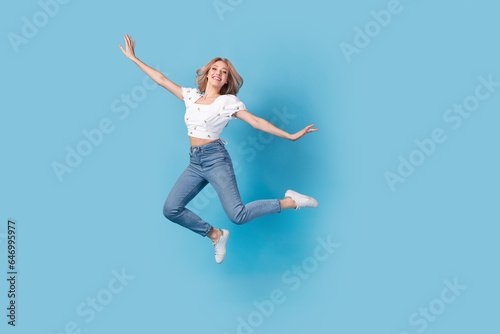 Full length photo of sweet carefree lady wear white blouse jumping high flying empty space isolated blue color background