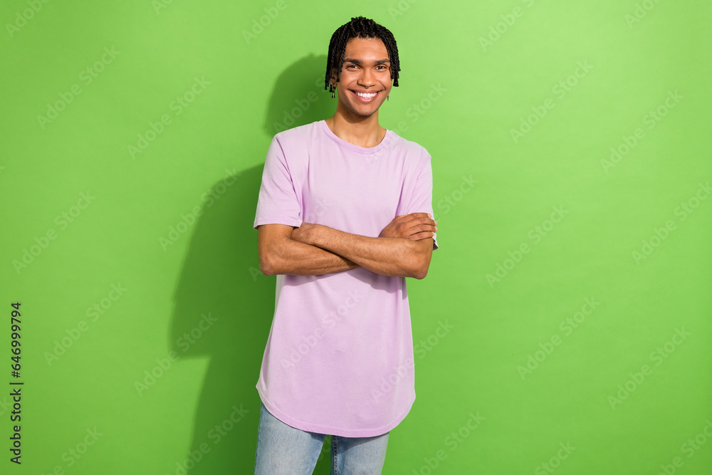 Photo of youngster model guy holding folded arms toothy smiling wearing oversize t-shirt isolated green color background Photo of youngster model guy holding folded arms toothy smiling wearing oversize t-shirt isolated green color background