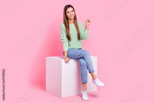 Full size body photo of girlish feminine woman sit empty space billboard podium direct finger novelty ad isolated on pink color background