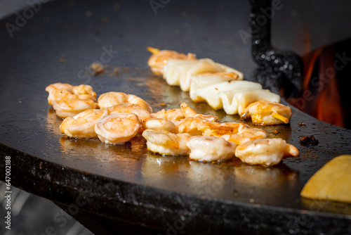 Grilling seafood. Shrimps and squids are cooked on wooden skewers over an open fire. Sea delicacies. Street food