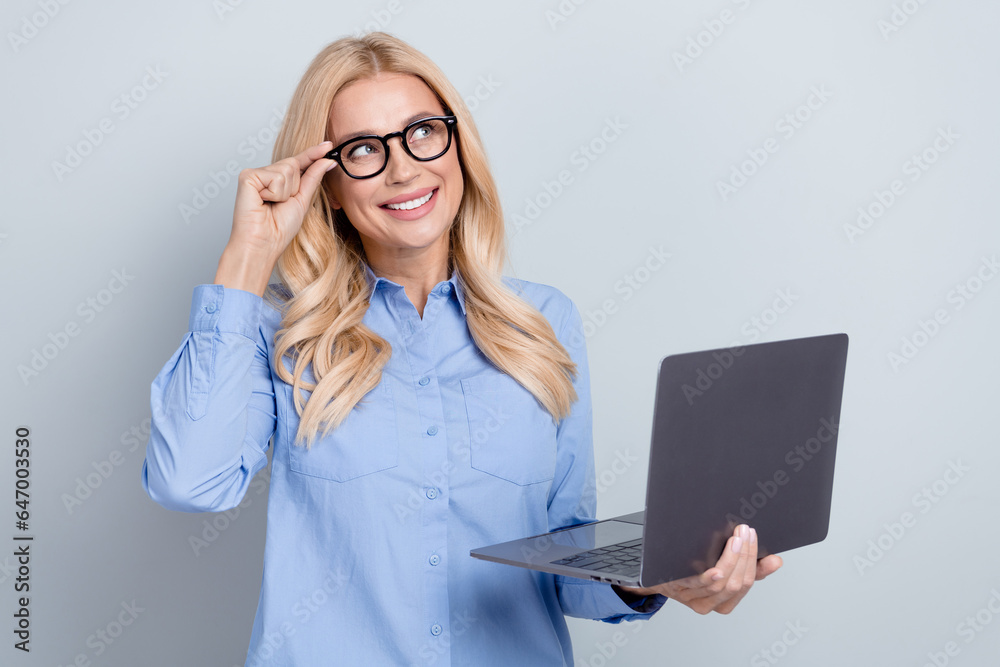 Photo of hr manager touch glasses worker young woman look empty space holding laptop hiring students isolated on grey color background Photo of hr manager touch glasses worker young woman look empty space holding laptop hiring students isolated on grey color background