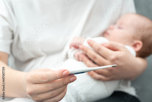 Concerned mother checks for fever in her newborn. Concept of infant health vigilance