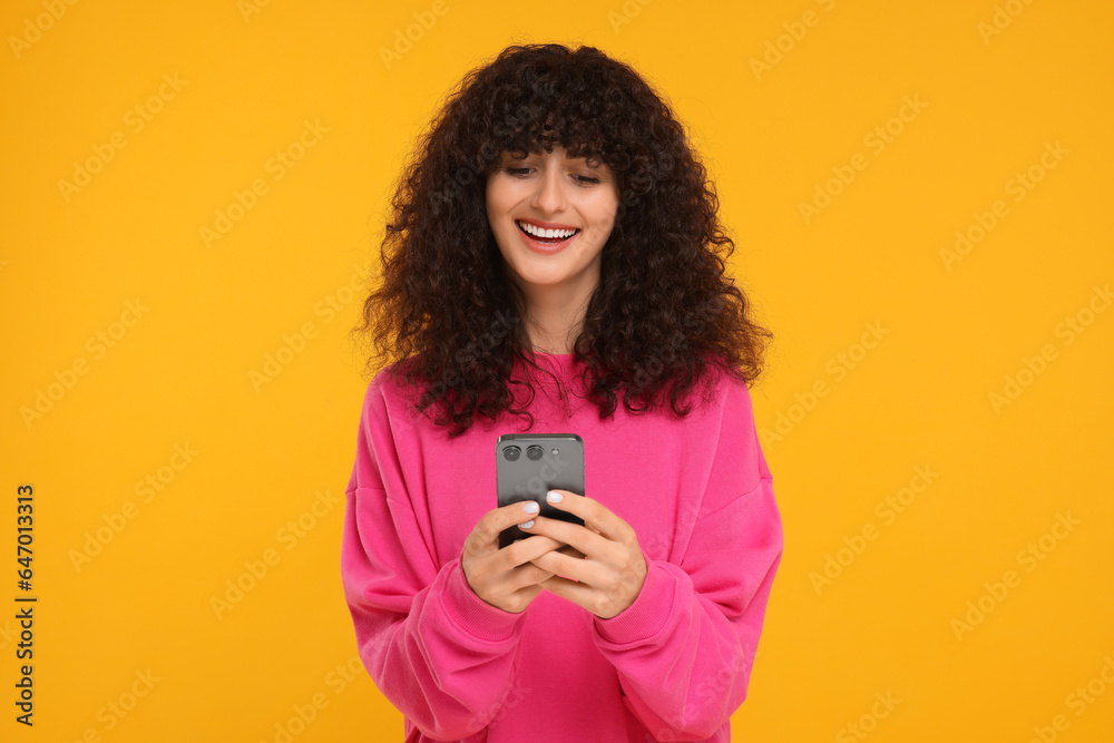 Happy young woman using smartphone on yellow background Happy young woman using smartphone on yellow background