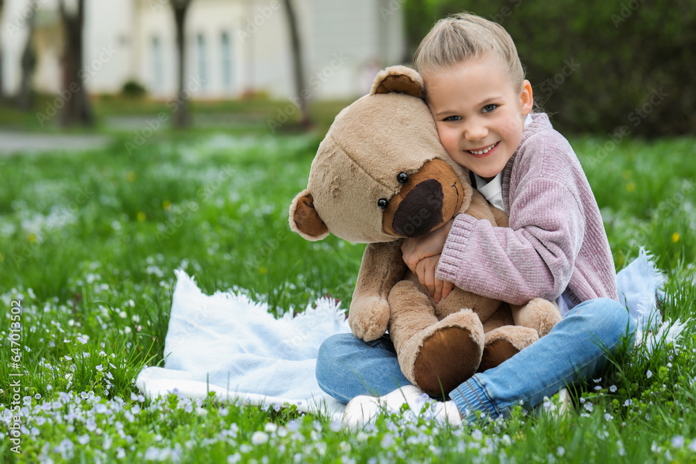 Little girl with teddy bear on plaid outdoors. Space for text Little girl with teddy bear on plaid outdoors. Space for text
