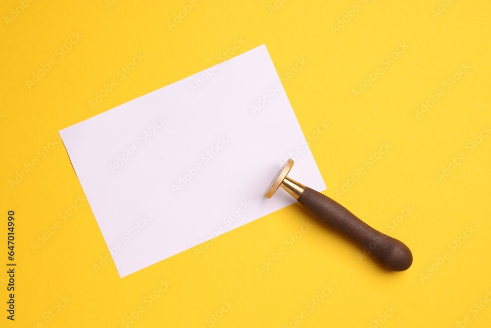 One stamp tool and sheet of paper on yellow background, top view. Space for text