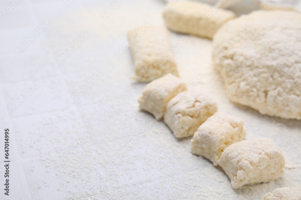 Making lazy dumplings. Raw dough and flour on white tiled table, closeup. Space for text