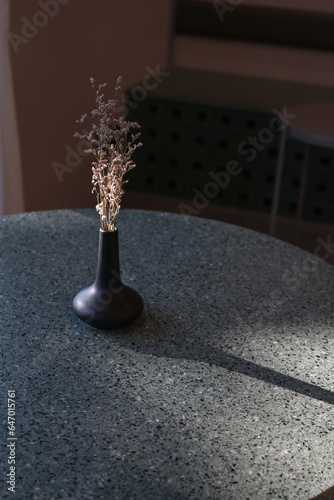 Dry grass bouquet flower in vase with warm shadows from sunlight on wooden table. Scandinavian vase on the table with copy space, minimal aesthetic style