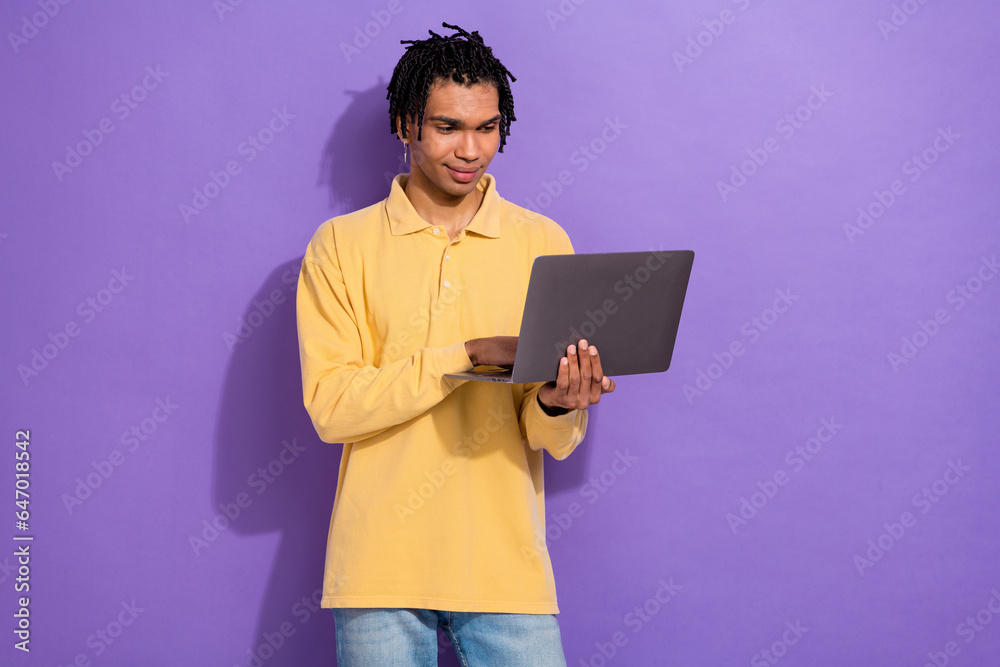 Photo of clever focused person with cornrows wear stylish shirt look at laptop texting email isolated on purple color background Photo of clever focused person with cornrows wear stylish shirt look at laptop texting email isolated on purple color background