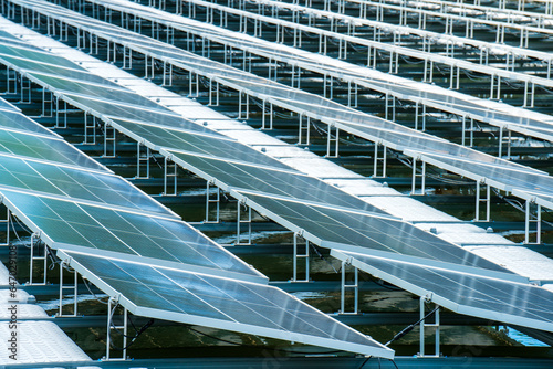 Side view of solar panels floating on water in a lake, for generating electricity from sunlight, selective focus, soft focus.