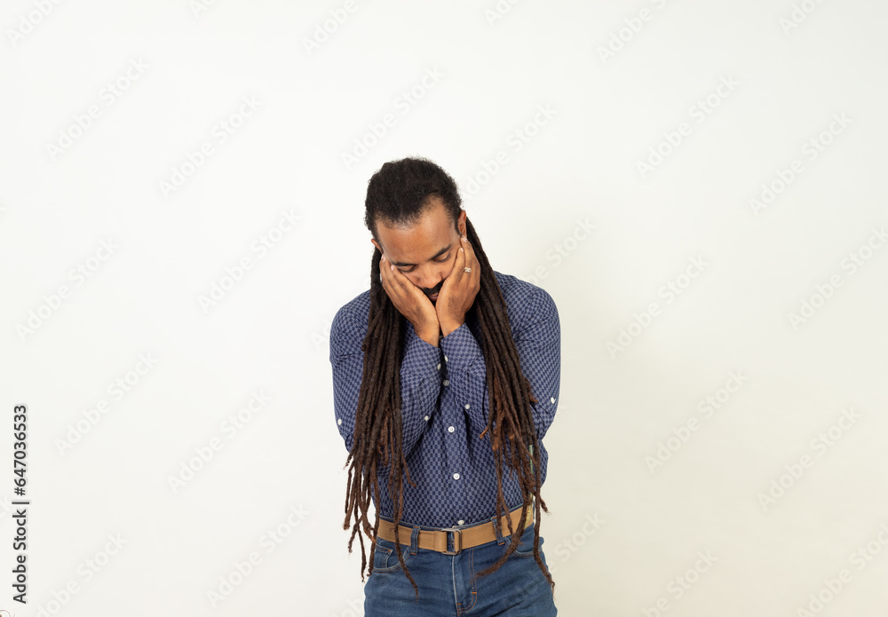 Sad Latino man with rasta hair and beard dressed in blue on a white background Sad Latino man with rasta hair and beard dressed in blue on a white background