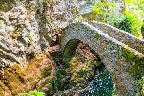 Old small stone bridge over river at Gorges de l'Areuse, Switzerland photo