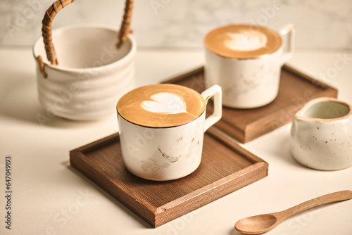 Two cups of coffee sit on a wooden serving board.
