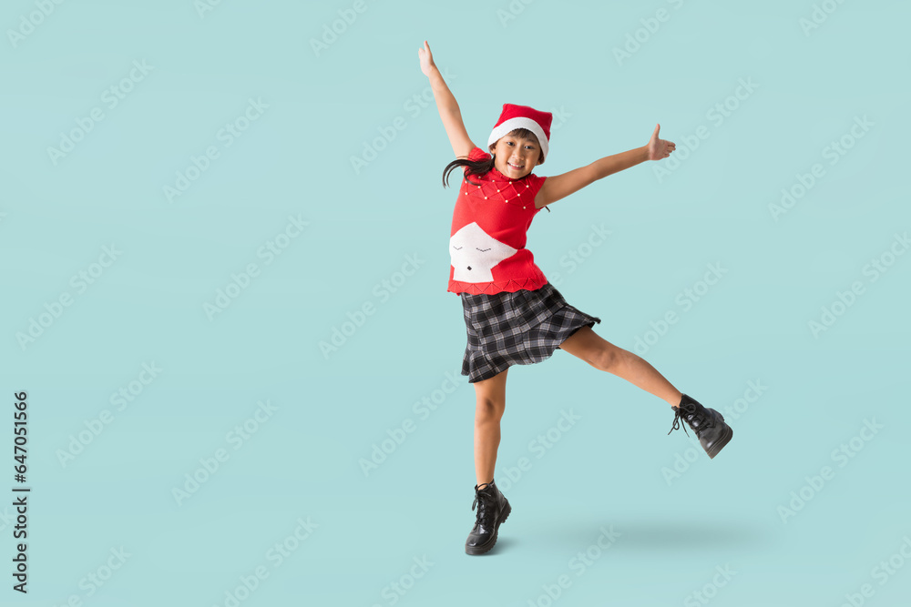 Happy smiling Asian child girl with wearing a red Christmas costume and Santa Claus hat, Celebration dancing and jumping have fun full body portrait, isolated on pastel plain light blue background. Happy smiling Asian child girl with wearing a red Christmas costume and Santa Claus hat, Celebration dancing and jumping have fun full body portrait, isolated on pastel plain light blue background.