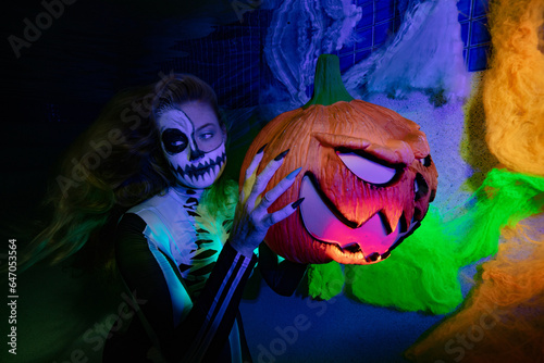 Fototapeta Naklejka Na Ścianę i Meble -  Halloween women holding a colourful pumpkin underwater in a pool with candys, skulls and spiders 