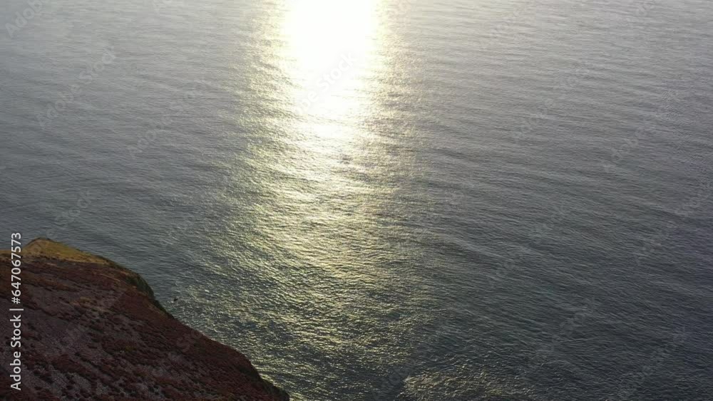 Drone shot tilting up while looking at the refection of sun rays on the ocean from sunset on the North Devon coast in the UK. Drone shot tilting up while looking at the refection of sun rays on the ocean from sunset on the North Devon coast in the UK.