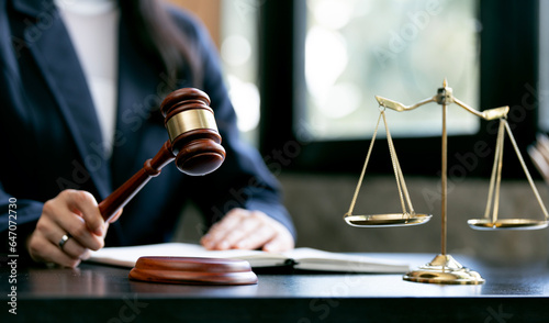 justice and law concept.Female judge holding wooden gavel in a courtroom on wooden table