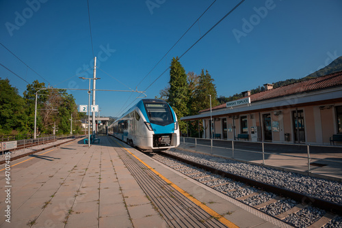 Modern passenger EMU train arriving to the train station of Rimske Toplice on a sunny summer day. Modern platform without shade.