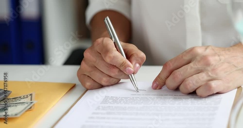 Businesswoman signing document holding pen puts signature on legal document. Seo gives permission for authorization signs contract and binds agreement photo