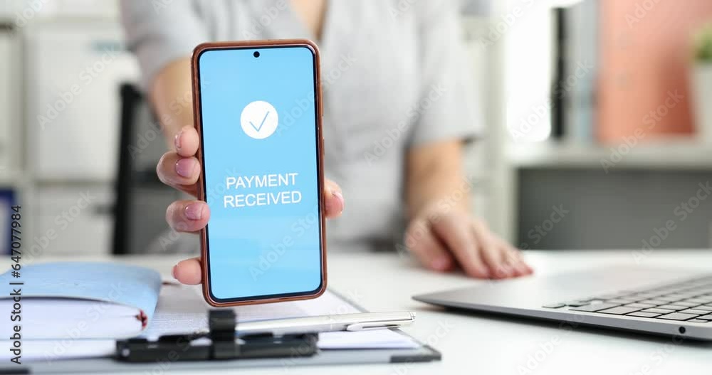 Hand holds smartphone with screen showing confirmation of receipt of payment and instant payment system. Online payments